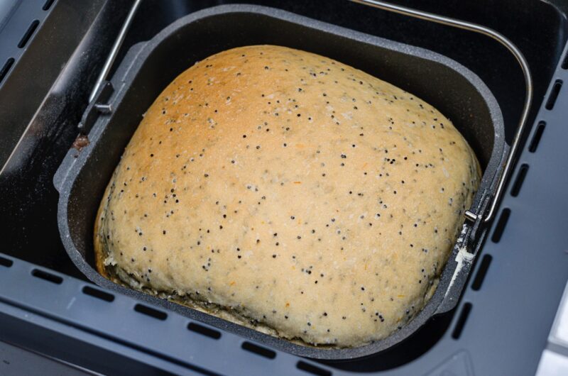 Bread machine with pan and fresh white bread at home.